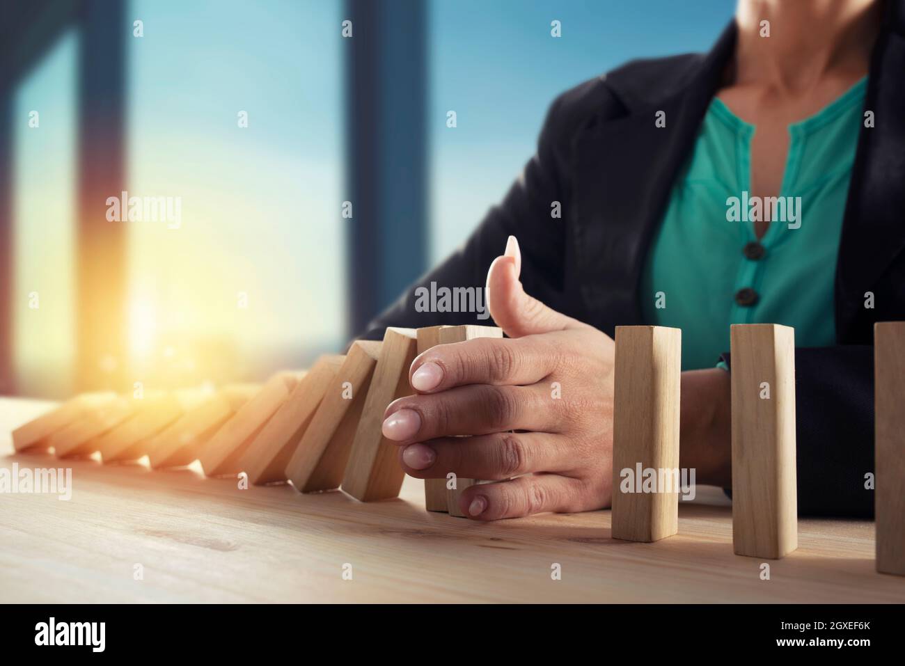 Imprenditrice si arresta una catena cadere come gioco di domino giocattolo. Concetto di prevenire le crisi e fallimento in business Foto Stock