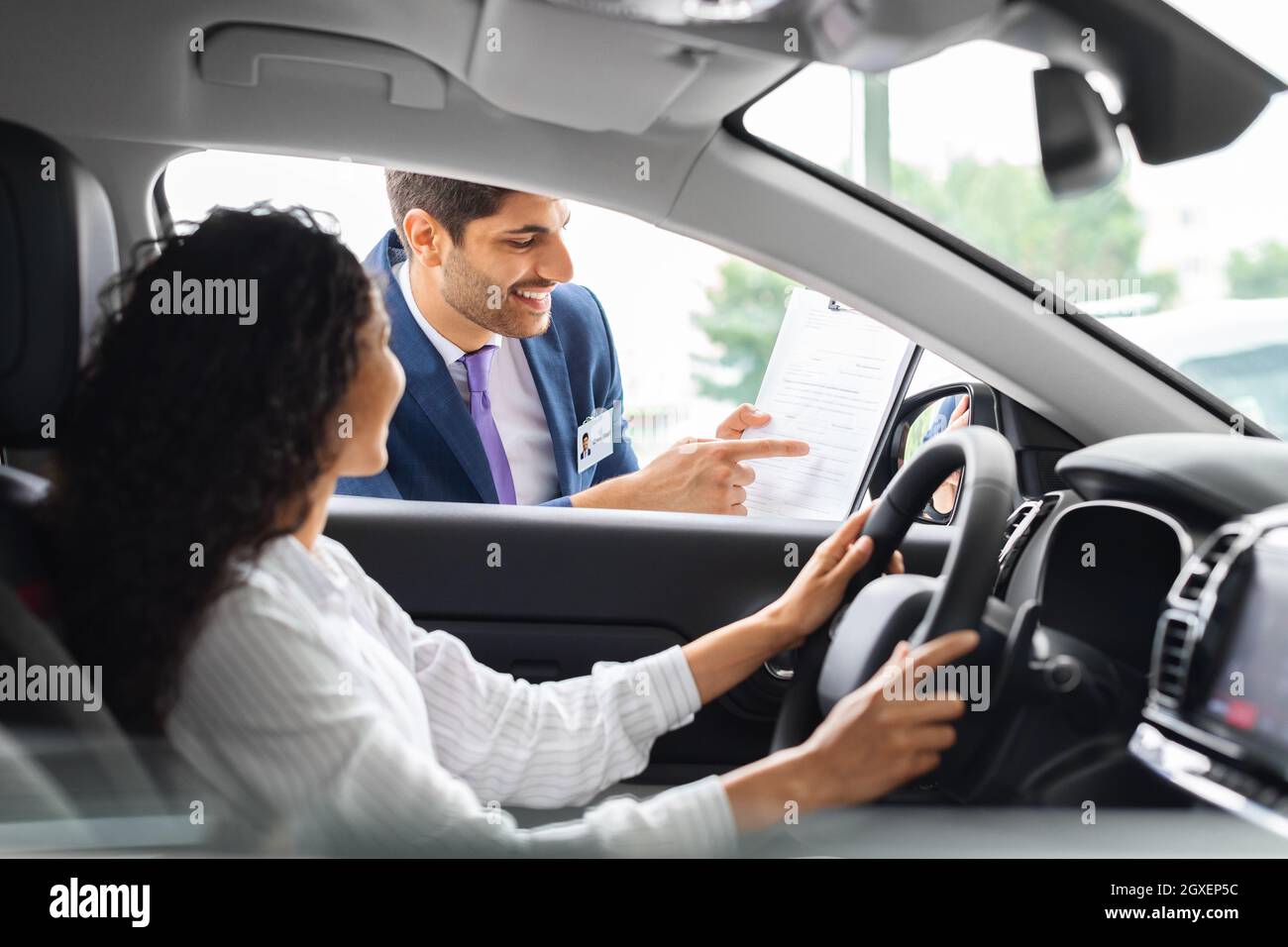 Giovane donna seduta all'interno dell'auto, che ha avuto una conversazione con il responsabile delle vendite Foto Stock