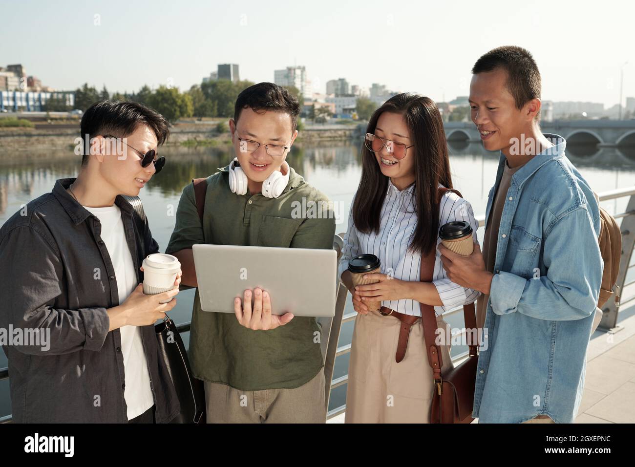 Quattro giovani colleghi cinesi con notebook che lavorano in rete all'aperto Foto Stock
