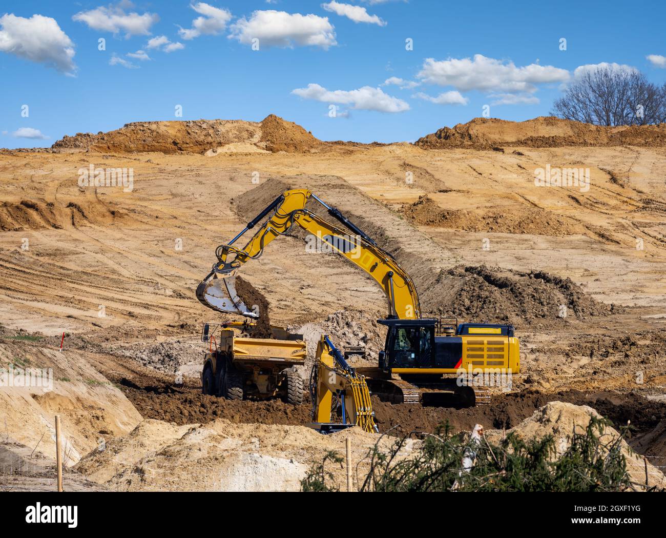 Falda terra gialla che riempie un autocarro in un cantiere Foto Stock