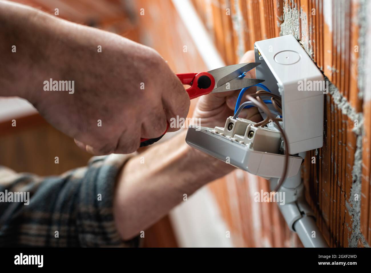 Vista dal basso. L'elettricista che lavora con le forbici prepara i cavi elettrici di un impianto elettrico. Industria edile. Foto Stock
