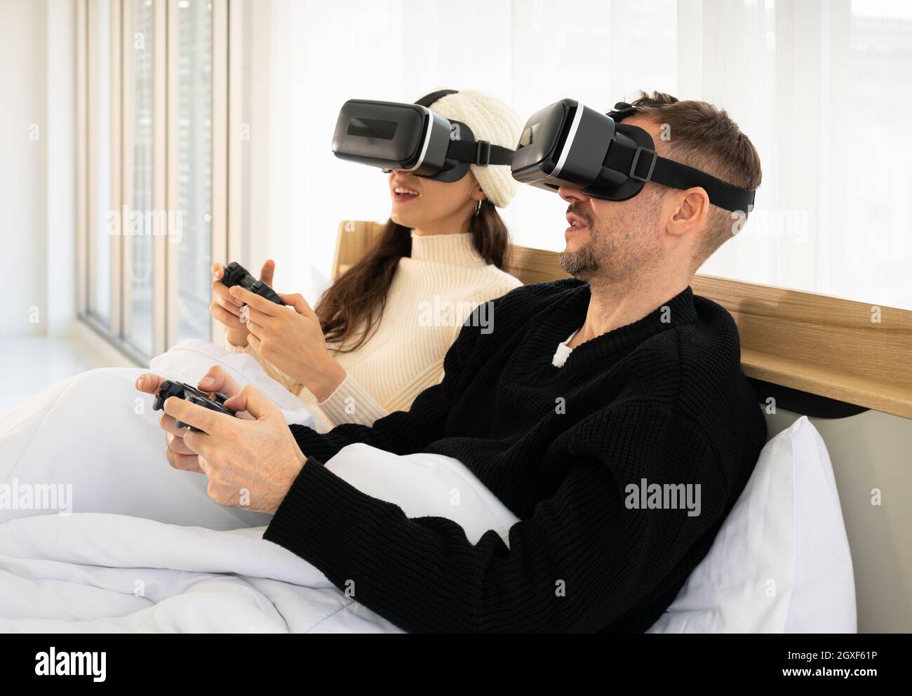Coppia sorridente con occhiali per realtà virtuale e giochi video con  controller a letto. Concetto di gaming e tecnologia Foto stock - Alamy