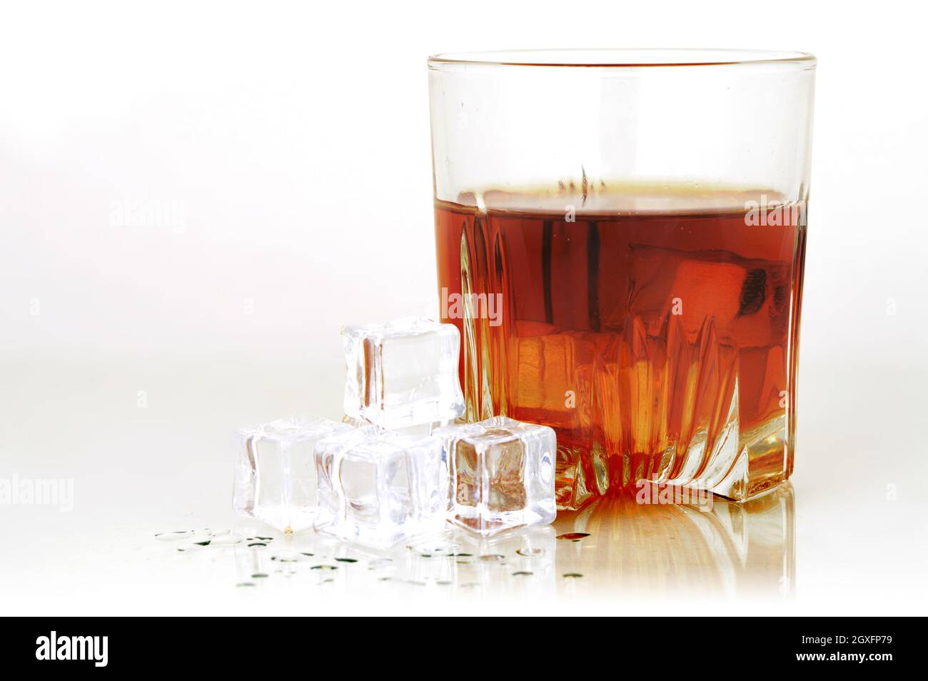 Un bicchiere freddo di whiskey servito con ghiaccio su sfondo bianco e grigio affumicato. Foto Stock