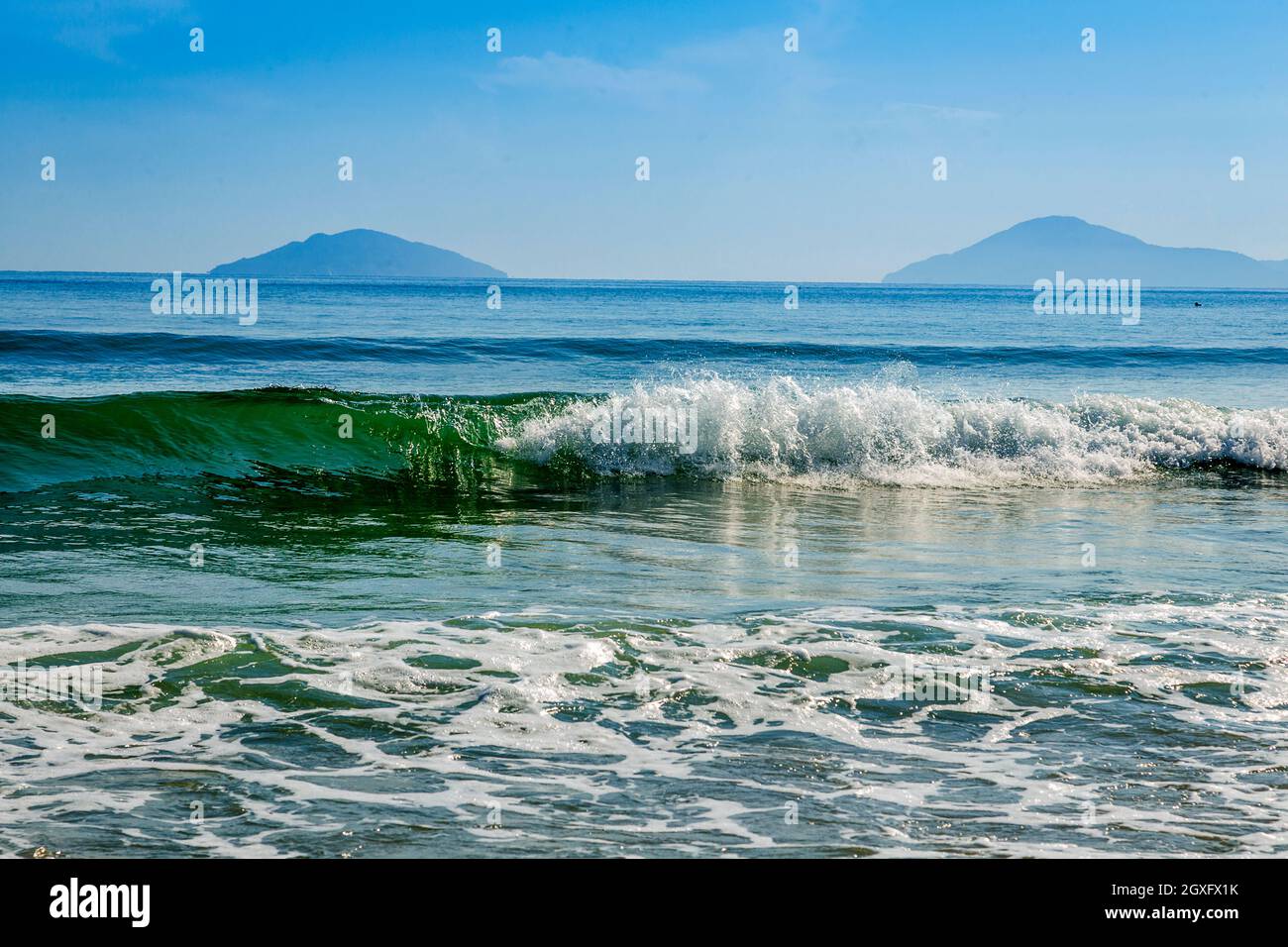 Una spiaggia di Bang con un'isola Cham sullo sfondo e onde curling in primo piano. Foto Stock