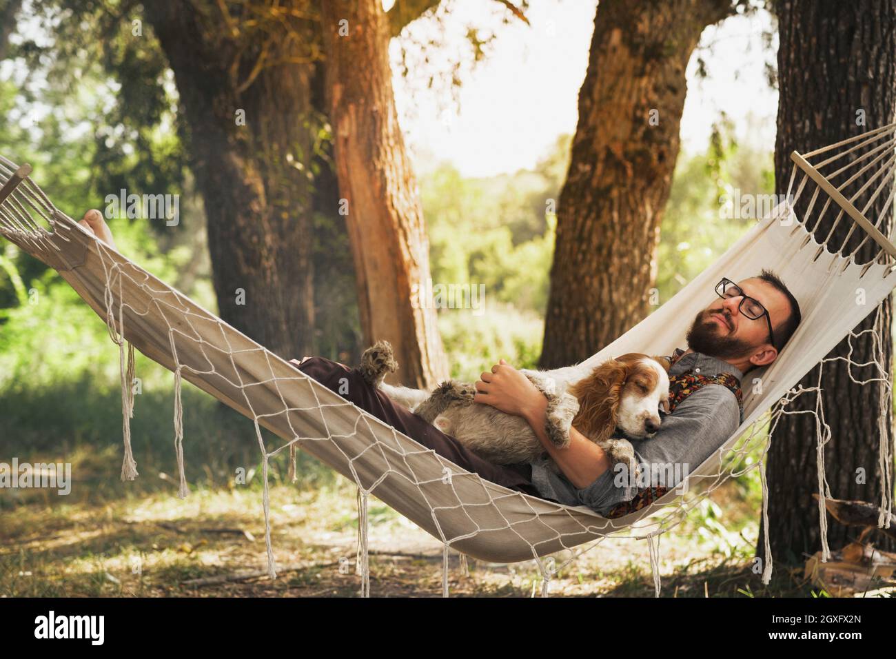 Persona che dorme con il suo cane in un'amaca nella bella scena estiva Foto Stock