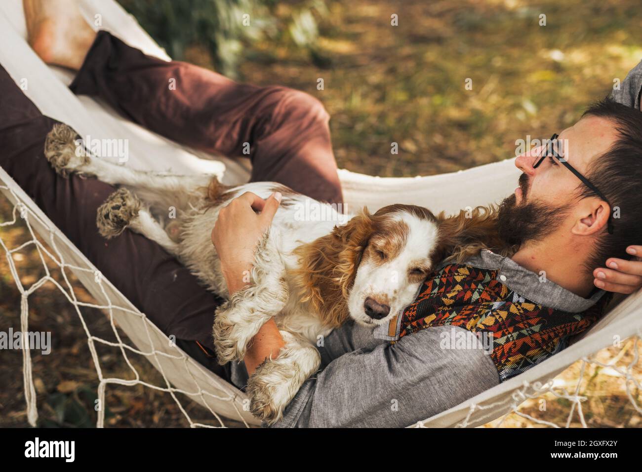 Persona che dorme con il suo cane in un'amaca nella bella scena estiva Foto Stock