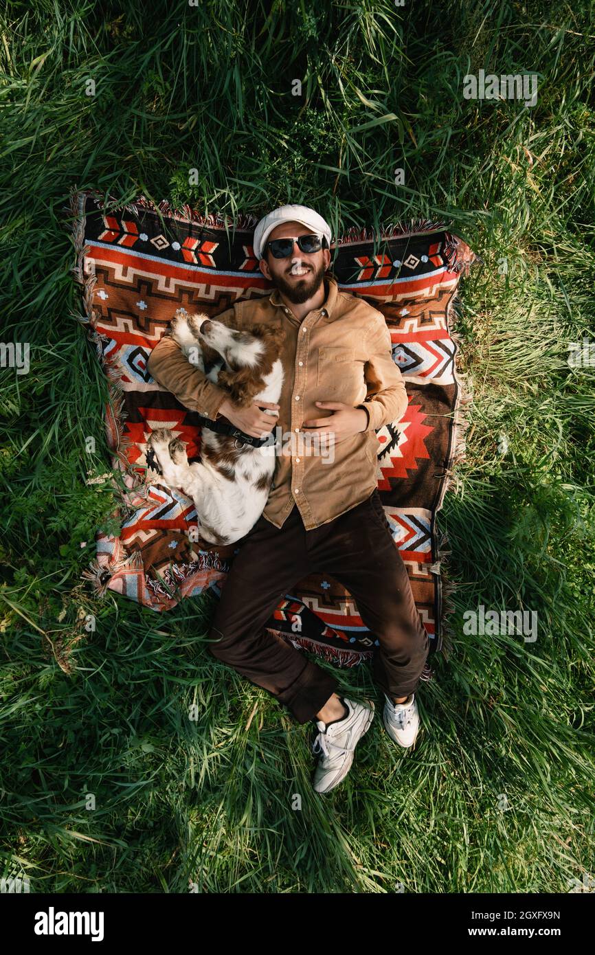 Vista dall'alto di un uomo e di un cane che riposano sull'erba verde in estate Foto Stock