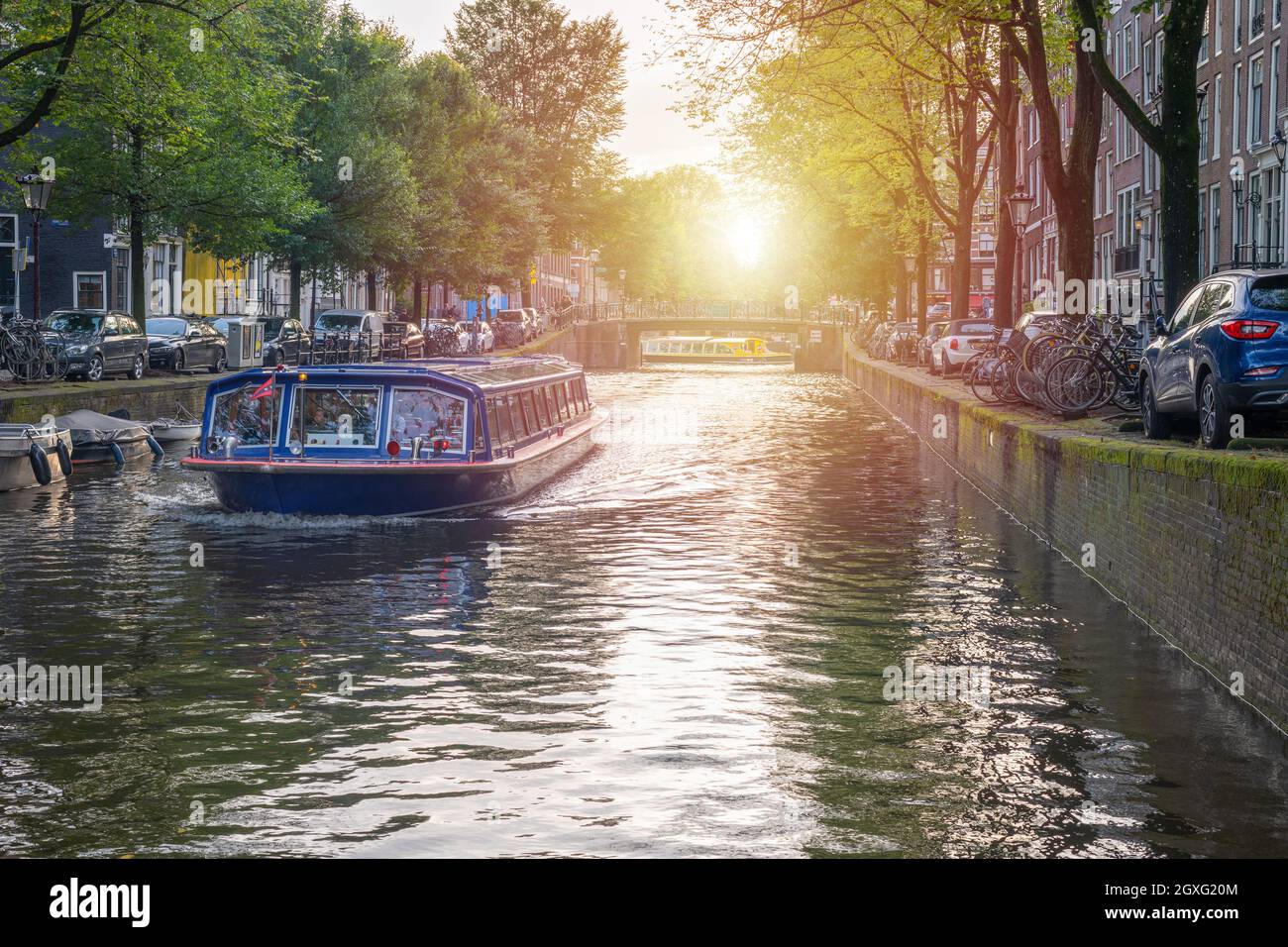 Tourboat nei canali di Amsterdam, Olanda al tramonto Foto Stock