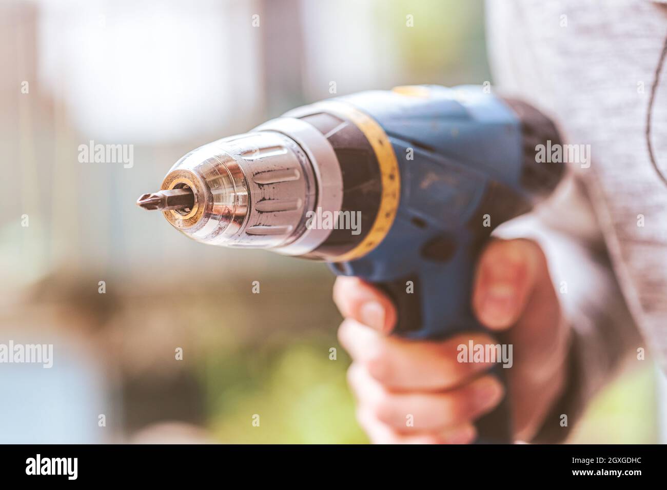 Fai da te il manipolo di casa sta tenendo un cacciavite cordless, all'aperto Foto Stock