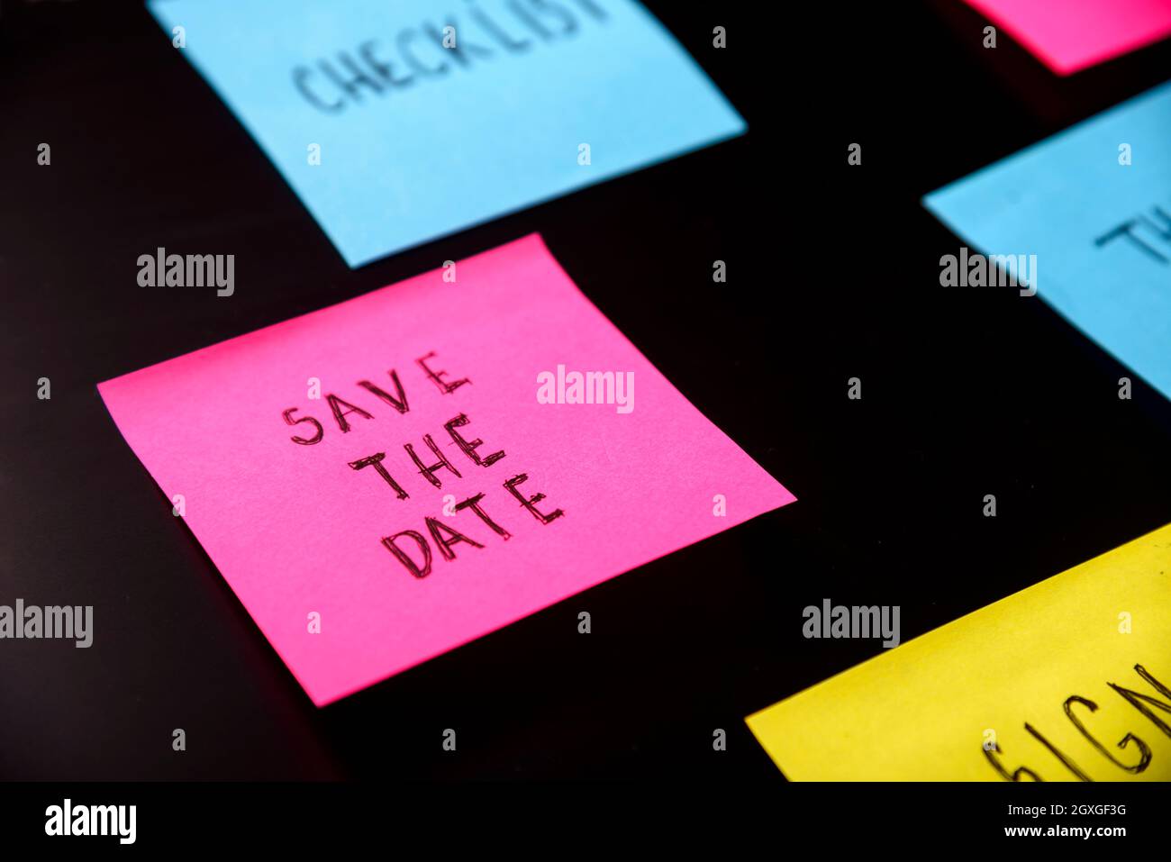 Note colorate appiccicose sul promemoria della lavagna nera. Salvare l'adesivo scritto della data su pineboard. Ricordarsi di salvare il concetto di business della data. Foto Stock