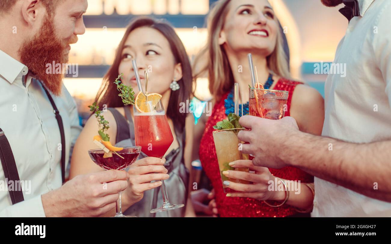 Primo piano di coppie multietniche che si godono i colorati cocktail al bar Foto Stock