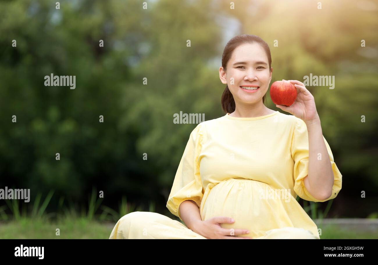 Donna incinta che mangia fragola che riposa all'aperto Foto Stock