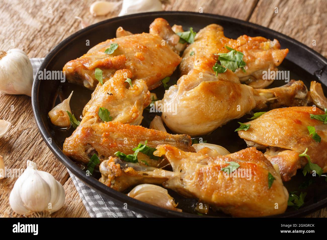 Pollo di cucina spagnola fritto con aglio, timo e rosmarino primo piano in un piatto sul tavolo. Orizzontale Foto Stock