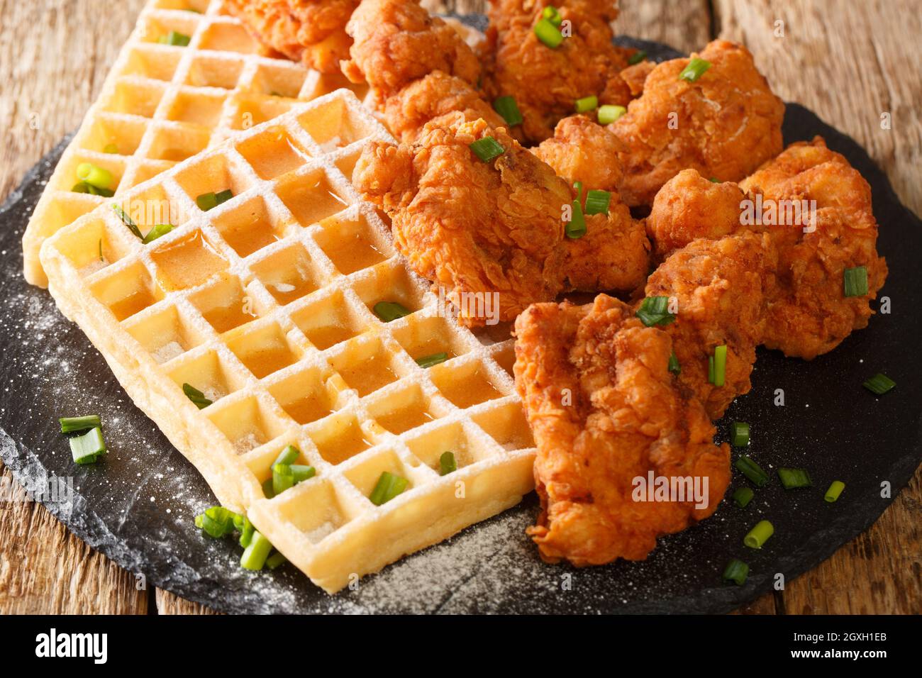 Il pollo e i waffle fatti in casa sono un piatto di soul food che tutti amano da vicino nel piatto di ardesia sul tavolo. Orizzontale Foto Stock