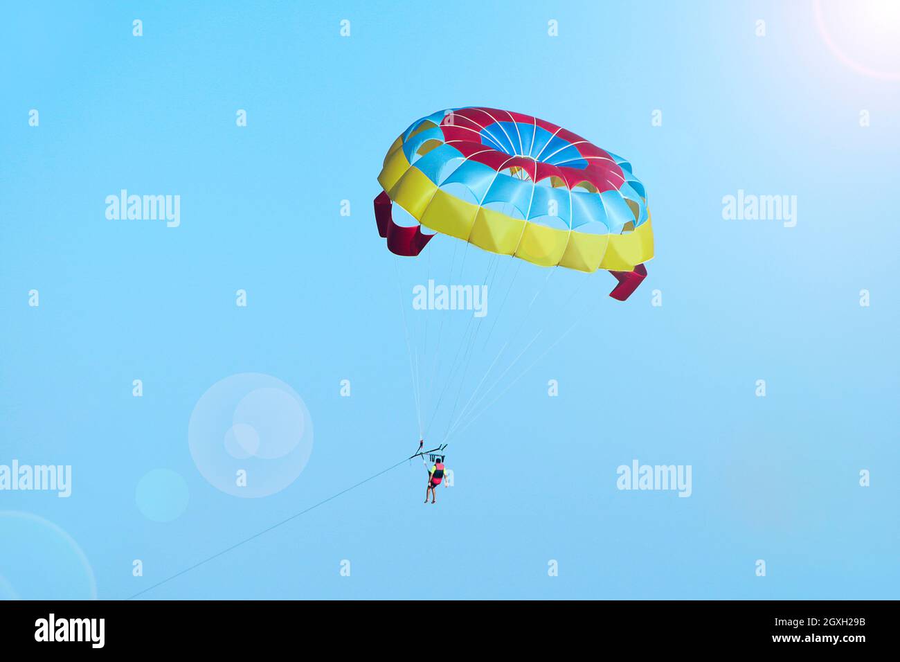 L'uomo è appassionato di parasailing lungo il cielo. Volo libero con paracadute. Uomo in aria. Concetto di viaggio. Volo su paracadute alto nel cielo blu Foto Stock