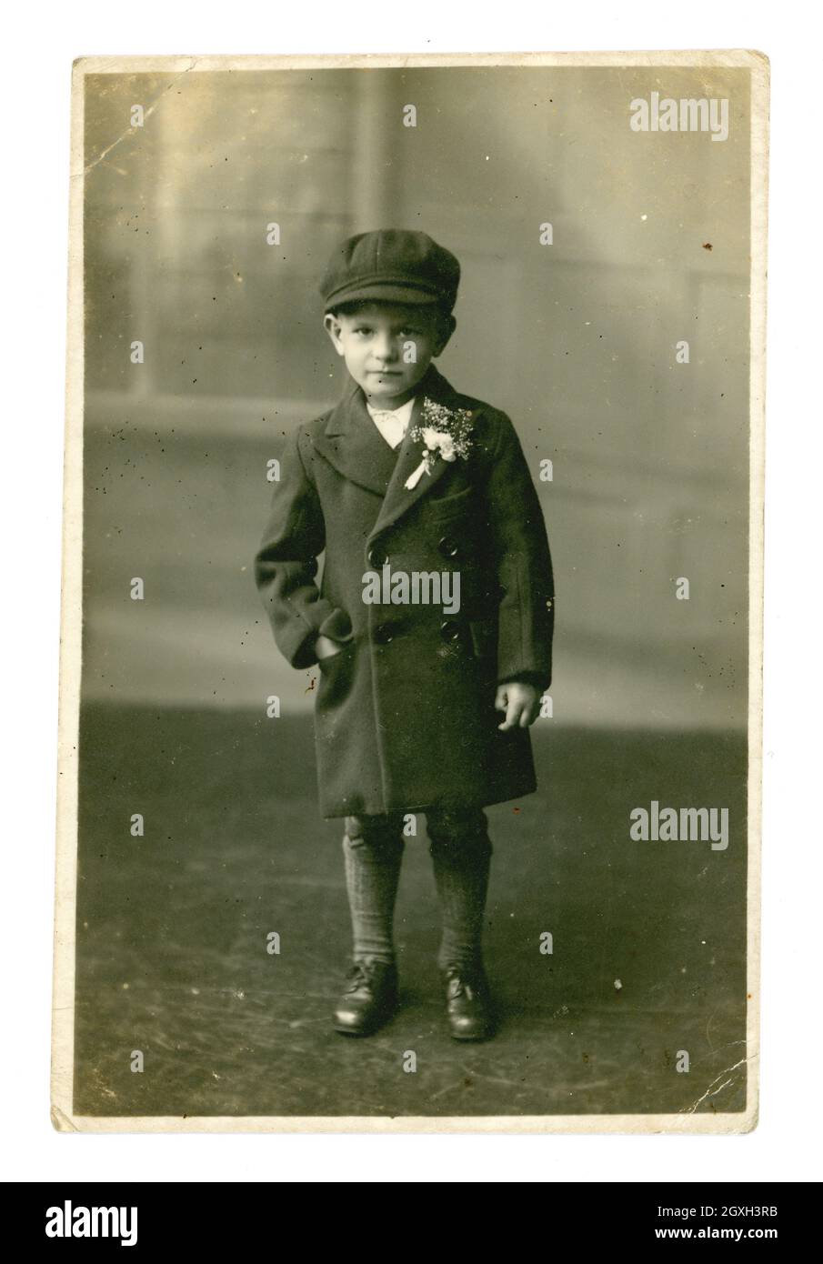 Ritratto originale da cartolina dei primi anni '1940 di un giovane giovane ragazzo della classe operaia dall'aspetto serio che indossa una giacca lunga intelligente, con fiori a bottone sul risvolto e un berretto piatto. il bambino del 1940. il figlio di 1940 anni. i figli dei 1940 anni. Forse è un paginaio ad un matrimonio, Cheriton, Folkestone, Kent, Regno Unito, datato 6 luglio 1940 Foto Stock