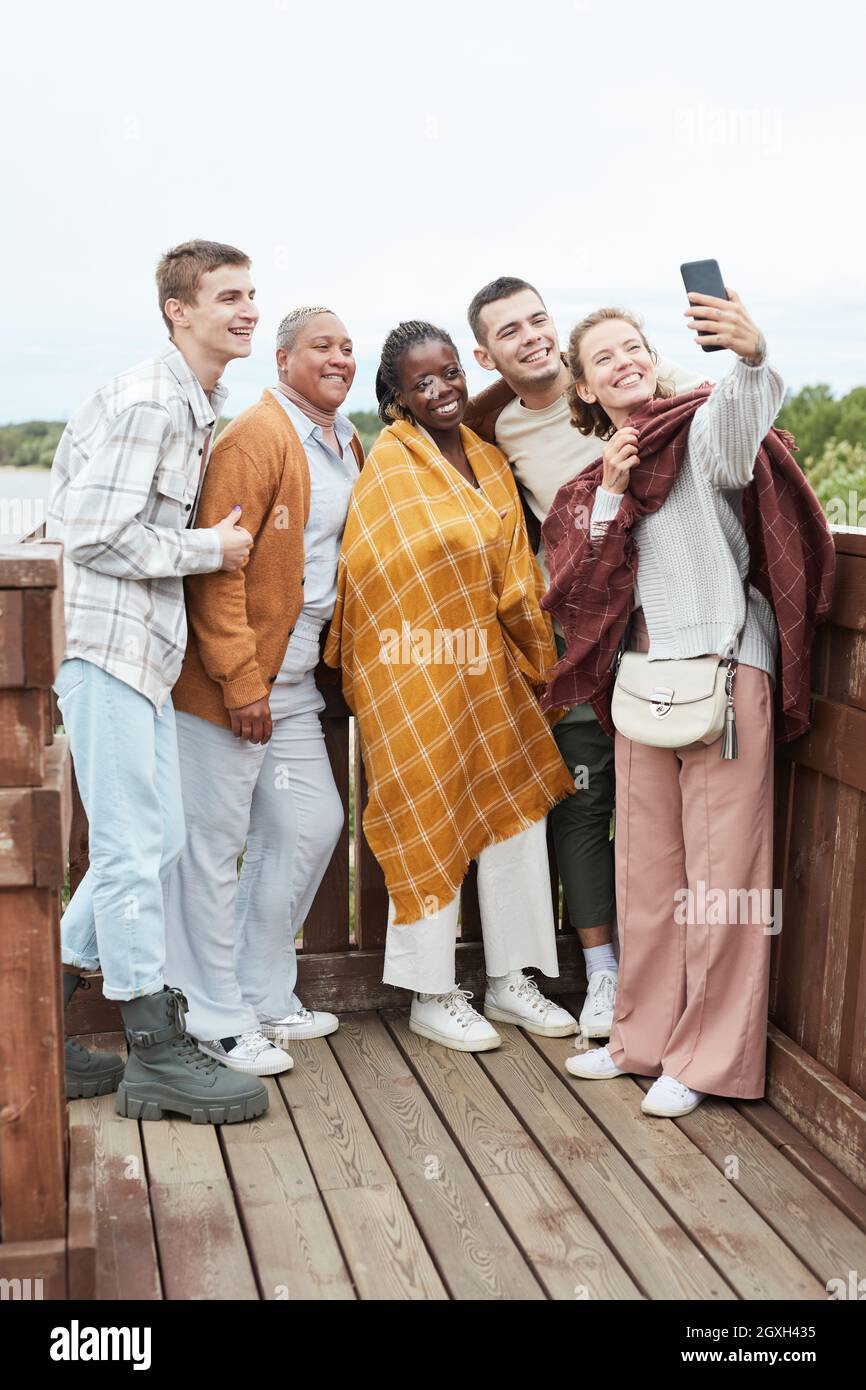 Ritratto a tutta lunghezza di diversi gruppi di giovani amici che prendono selfie al punto di vista durante l'escursione Foto Stock