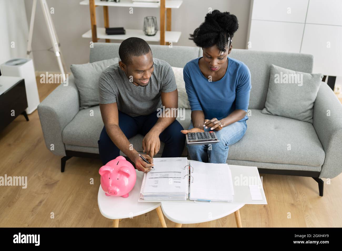 Felice coppia africana che fa il ritiro delle finanze piano e denaro bilancio Foto Stock