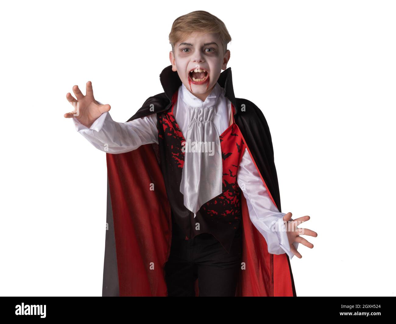 Ritratto di ragazzo che indossa vampiro di Halloween trucco e costume mantello nudo i suoi denti, isolato su sfondo bianco. Foto Stock