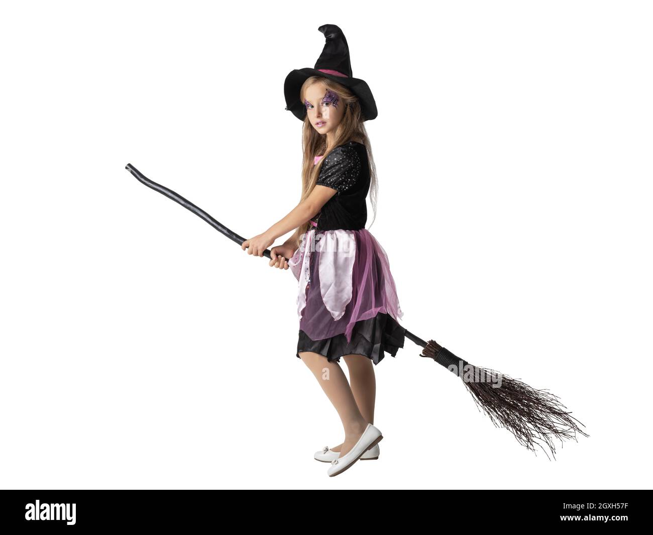 Halloween ragazza strega partito su scopa isolato su sfondo bianco, adorabile ragazzo cute giovane che agisce per essere strega in studio Foto Stock