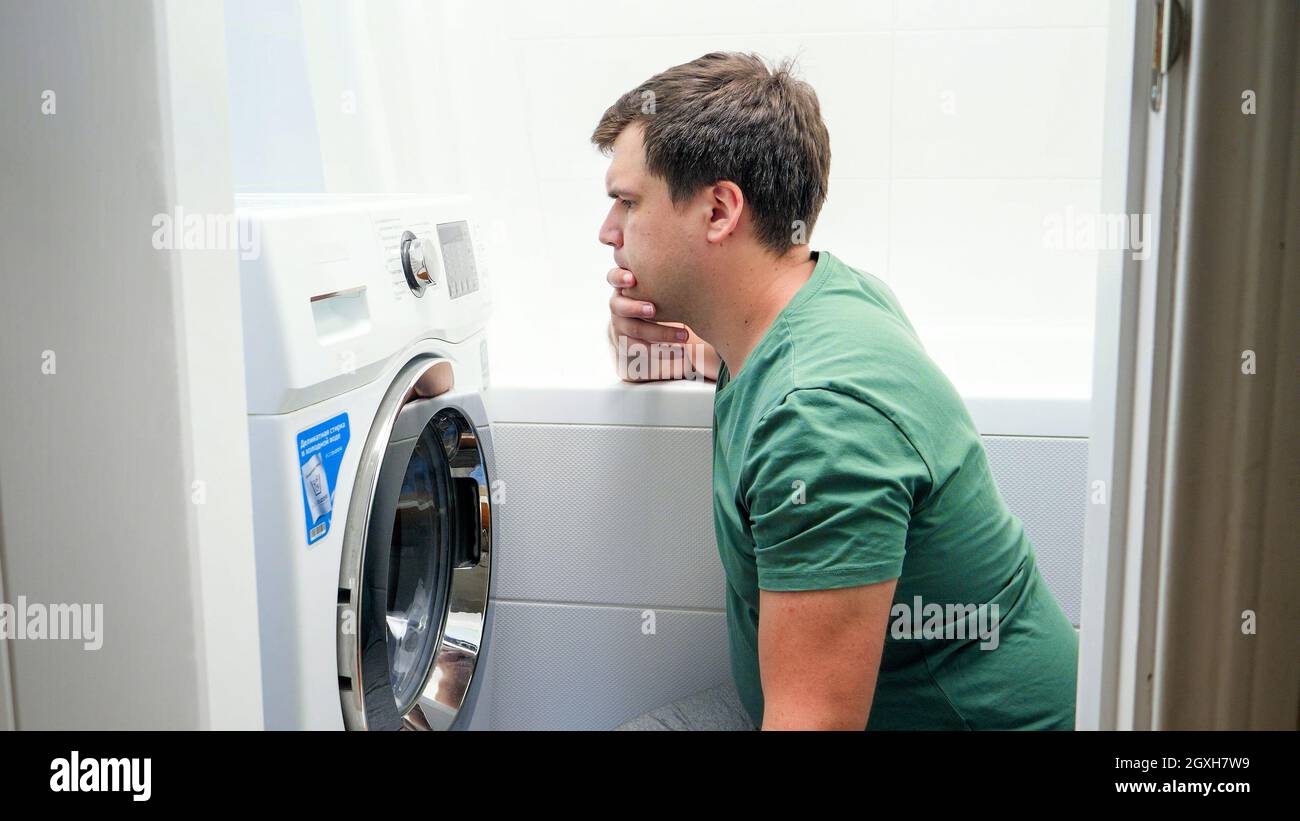 Uomo confuso impostazione lavatrice lavatrice. Maschio che lotta e  frustrante mentre fa il lavoro domestico e la routine quotidiana nel paese  Foto stock - Alamy
