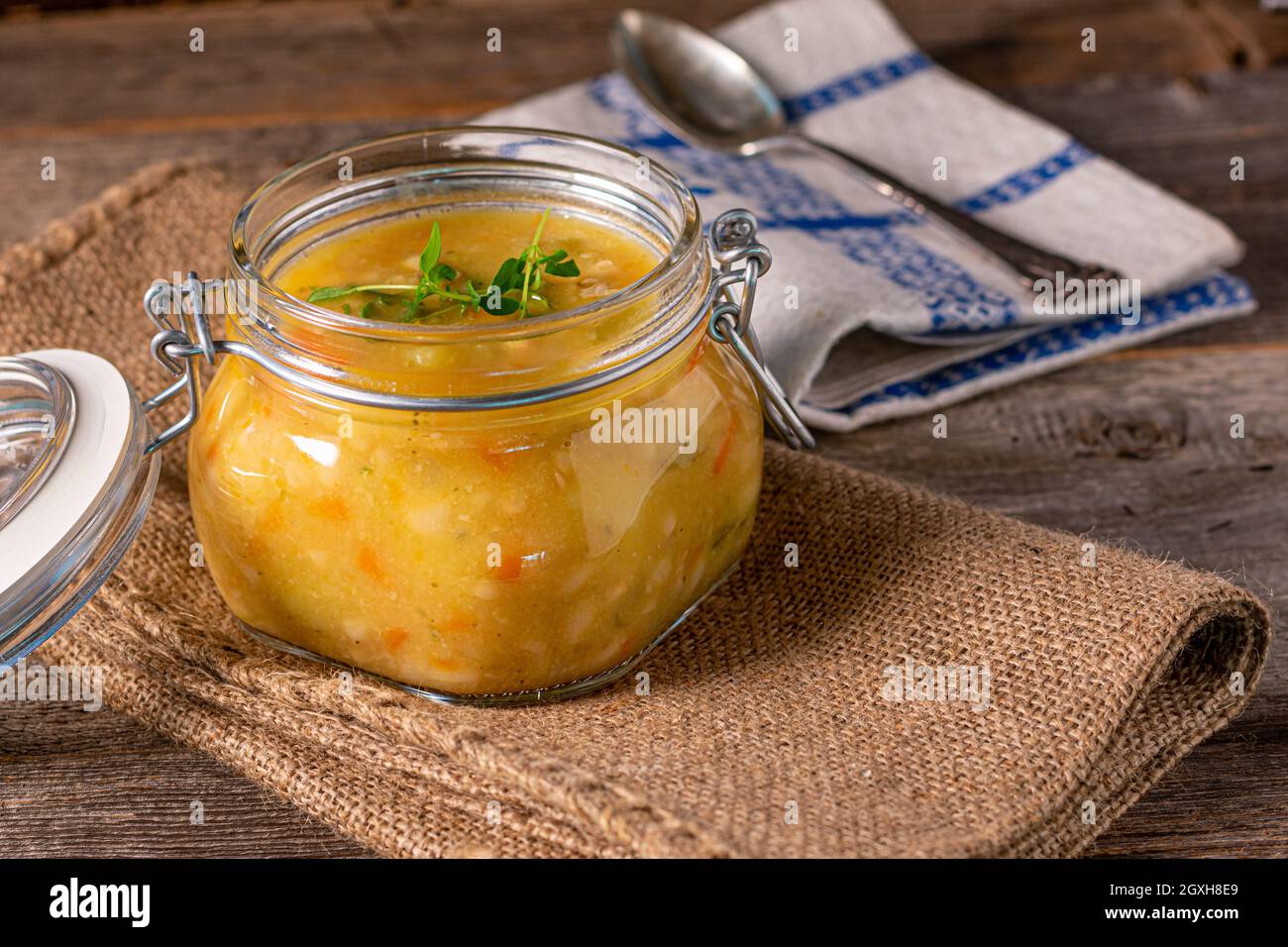 Zuppa fatta in casa o stufato con pollo, verdure e patate in un vaso su tavola di legno. Foto Stock