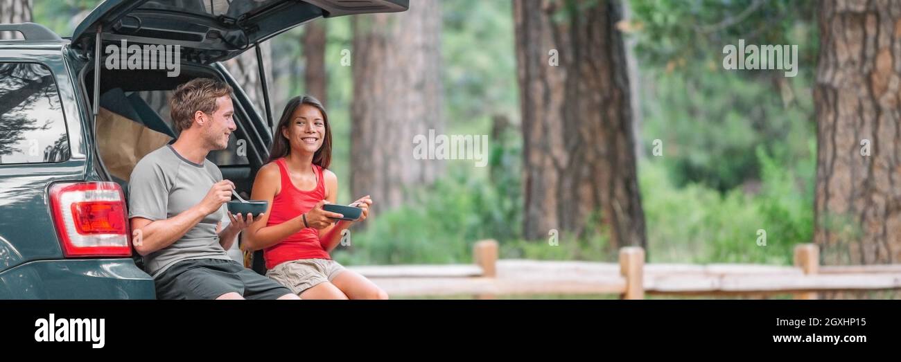 Viaggio su strada turista coppia mangiare pranzo cibo sul retro dell'auto in estate campeggio vacanza viaggio. Gente di guida felice Foto Stock