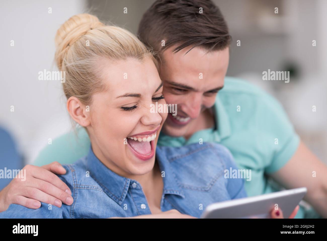 Coppia giovane in un momento di relax a casa di lusso con i computer tablet lettura in salotto sul divano del lettino. Foto Stock