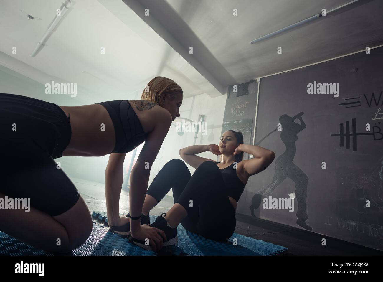 Donne in bianco e nero abbigliamento sportivo su un vero gruppo corpo combattimento allenamento in palestra treno per combattere, kickboxing con un allenatore. Foto Stock