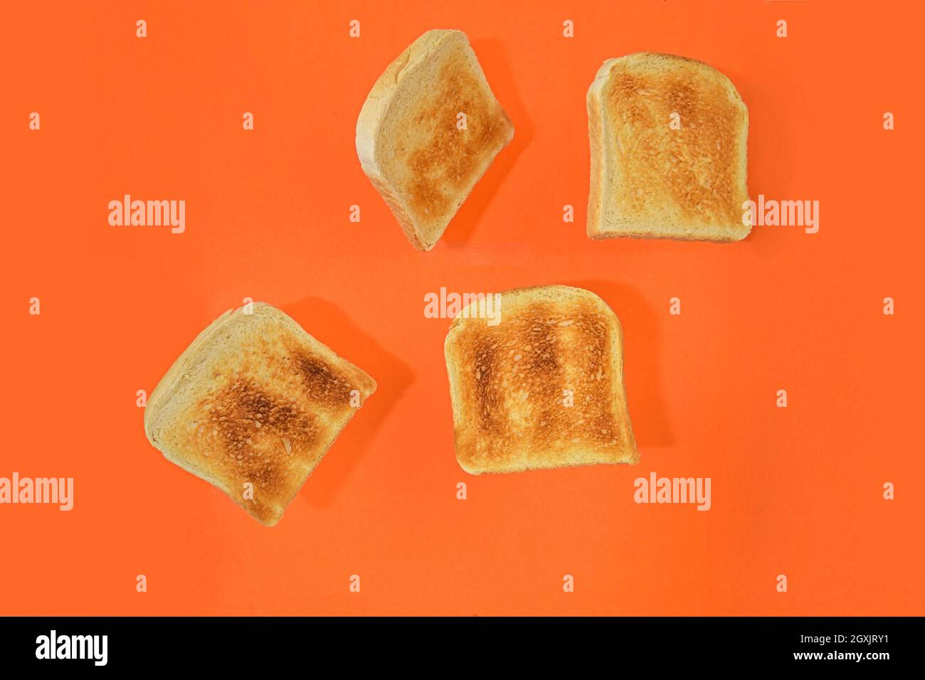 Pezzetti di pane volanti arrostiti su sfondo pastello arancione. Pezzi freschi di tostatura su sfondo arancione. Stile minimalista. Spazio per il testo Foto Stock
