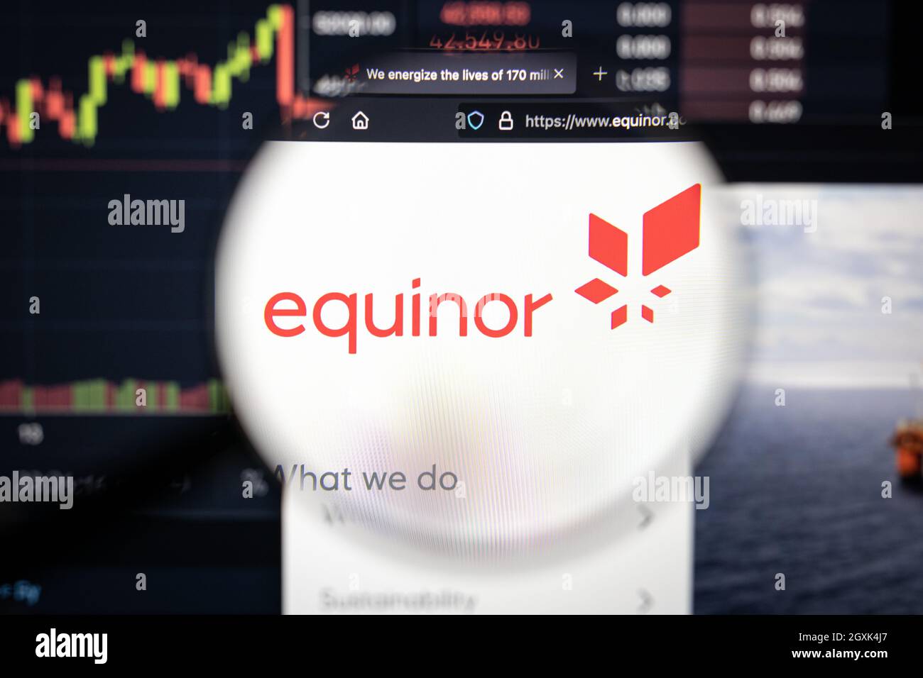 Logo aziendale di Equinor su un sito web con sviluppi sfocati del mercato azionario in background, visto su uno schermo del computer attraverso una lente di ingrandimento Foto Stock