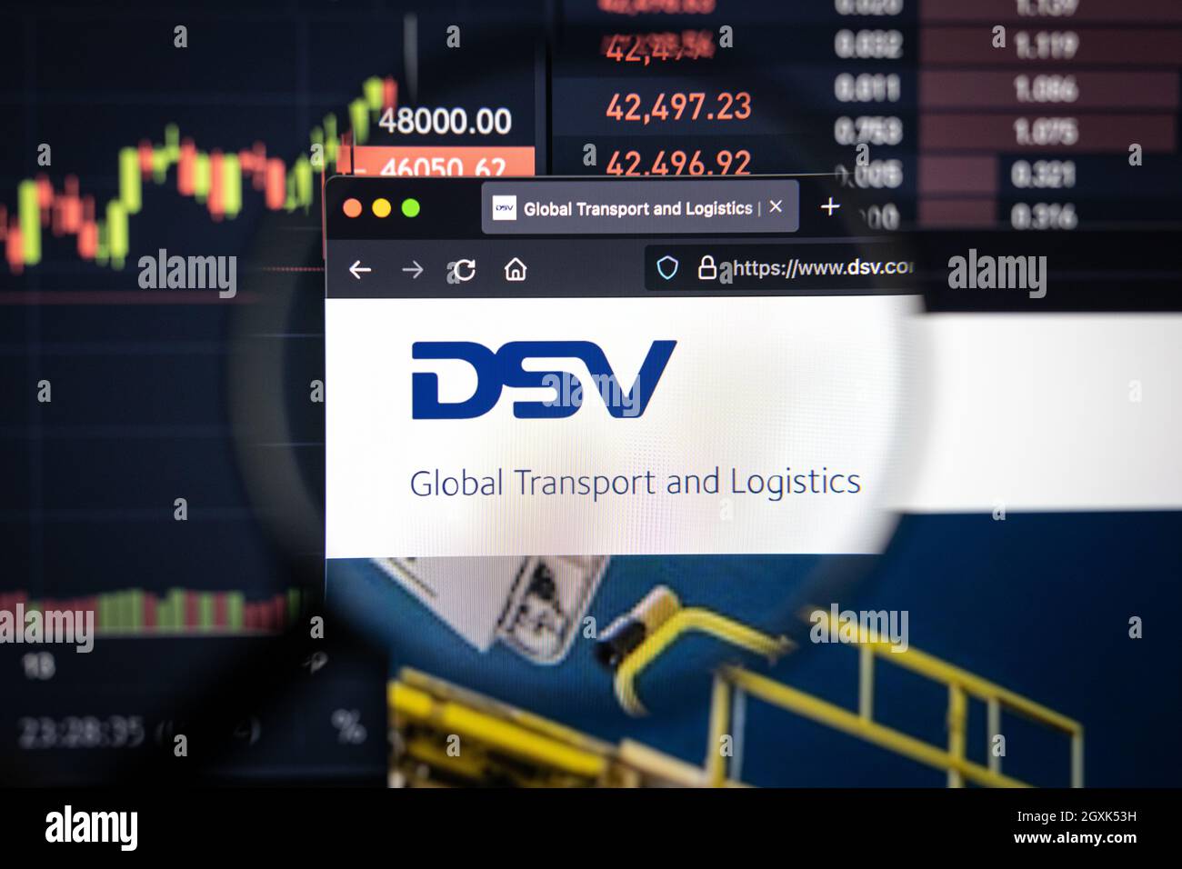 DSV Company logo su un sito web con blurry mercato azionario sviluppi in background, visto su uno schermo di computer attraverso una lente d'ingrandimento Foto Stock