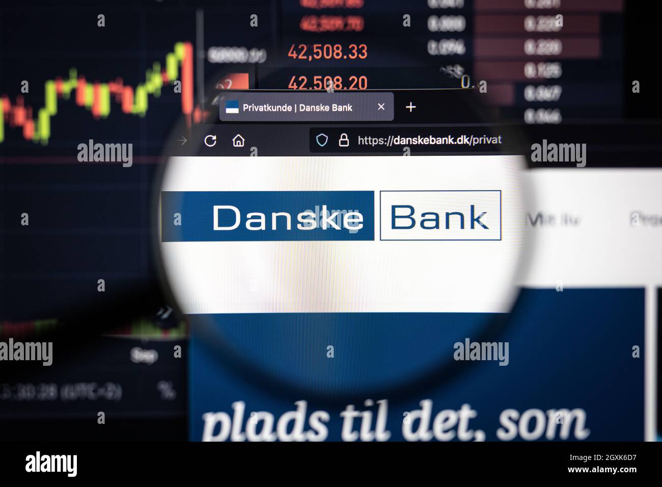 Danske Bank Company logo su un sito web con blurry mercato azionario sviluppi in background, visto su uno schermo del computer attraverso una lente d'ingrandimento Foto Stock