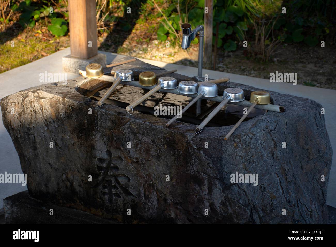 Ladles o hishaku disposti su un bacino di pietra o temizuya all'ingresso del tempio buddista di Kanjizai-ji, Ainan, Prefettura di Ehime, Giappone Foto Stock
