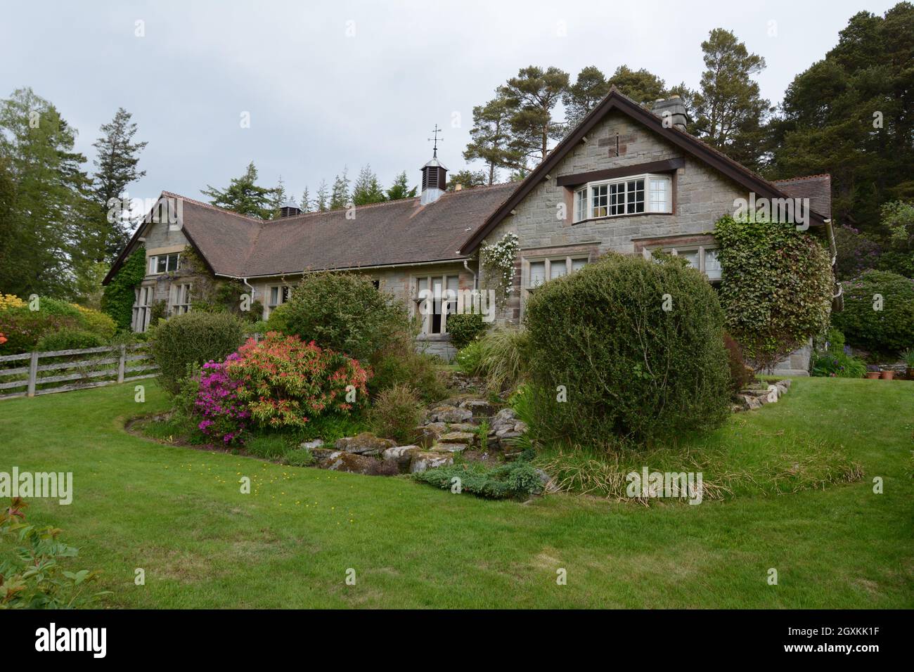 casa casa Lodge giardino piante piante Rhododendron Cragside Northumberland National Trust Bush colori alberi di colore collina pietre rocciose Foto Stock