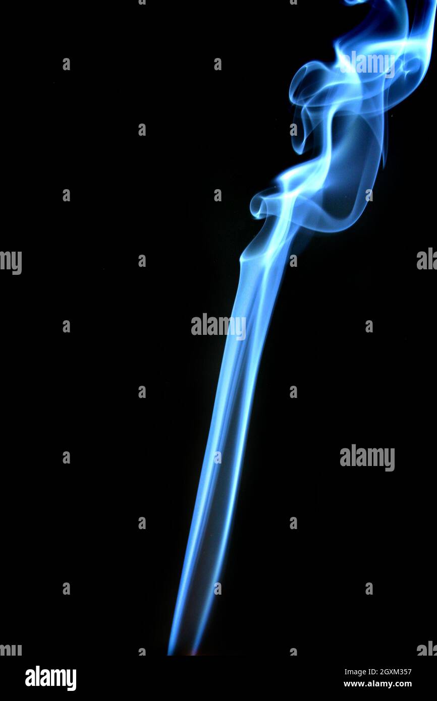 Fumo blu che si alza in forma astratta su sfondo nero Foto Stock