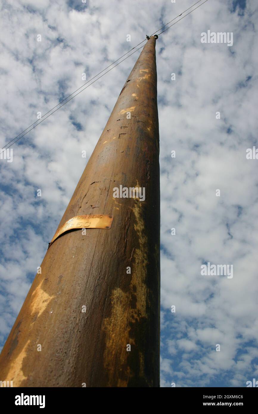 Un grande vecchio palo del telefono si allunga in su in un cielo nuvoloso Foto Stock