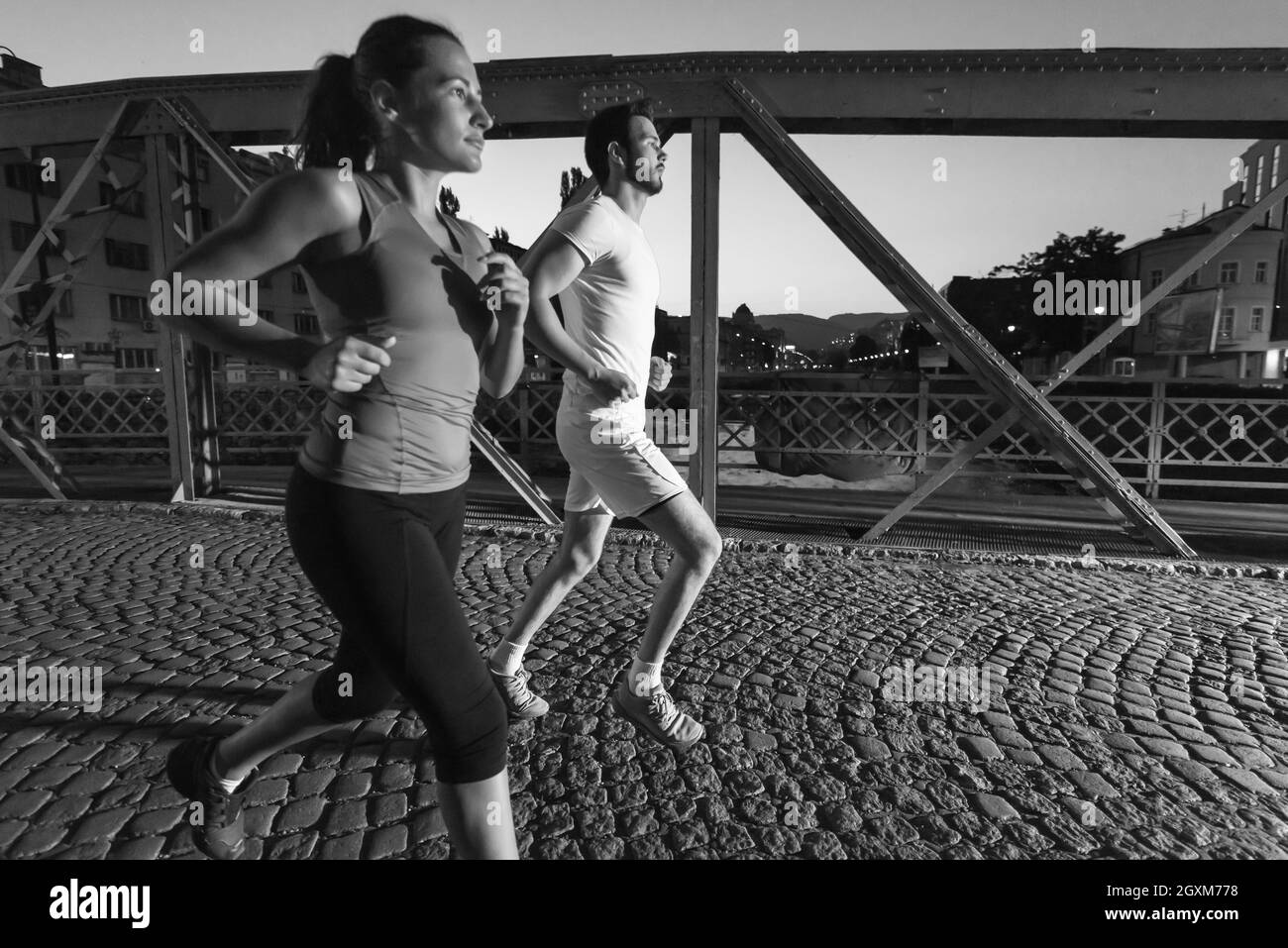 Urban sport, sano giovane jogging attraverso il ponte in città al mattino presto nella notte Foto Stock