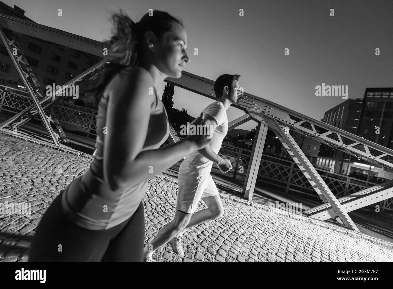 Urban sport, sano giovane jogging attraverso il ponte in città al mattino presto nella notte Foto Stock