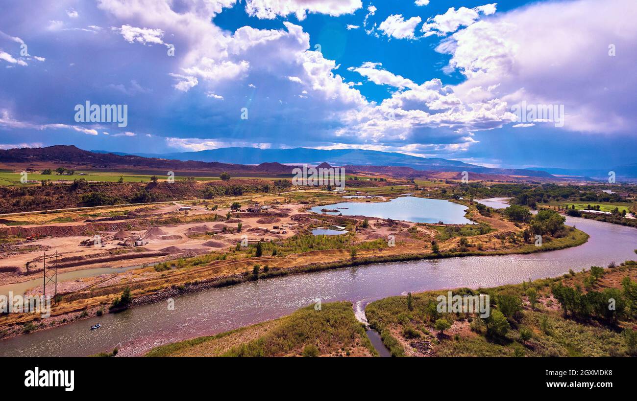 Fiume e stagno attraverso campi desertici con montagne e raggi di sole Foto Stock