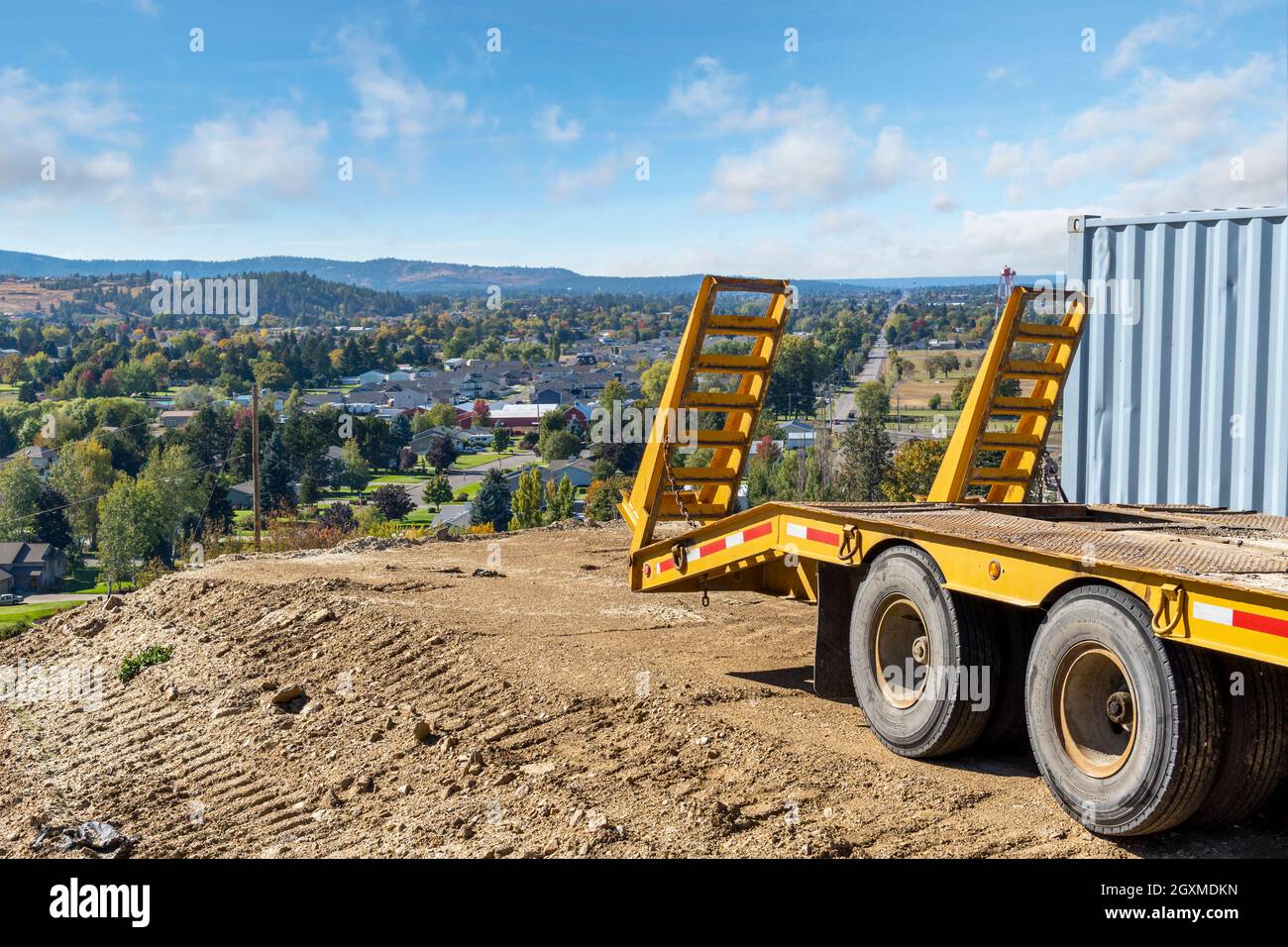 Un rimorchio trattore parcheggia sul bordo di un terreno collinare pronto per una nuova casa che si affaccia sulle città di Greenacres, Liberty Like, Spokane Washington Foto Stock