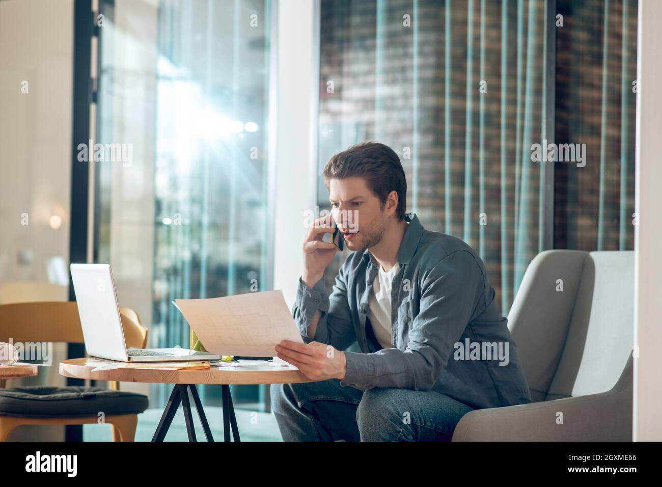 Uomo con documenti che parla sullo smartphone Foto Stock