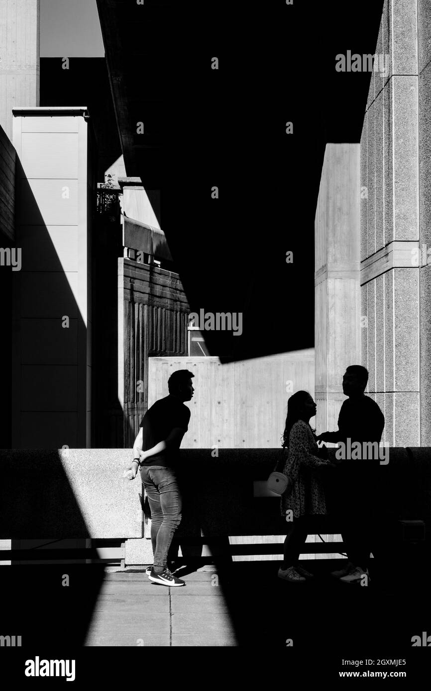 Fotografia di strada in bianco e nero a Londra: Tre figure con architettura astratta. Foto Stock