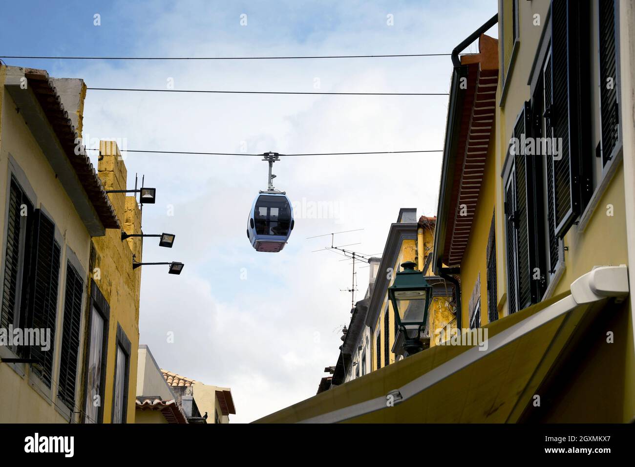 Funchal, Madeira, Portogallo - Febbraio 2016: Trasporto su una funivia che passa sopra gli edifici in una strada stretta nel quartiere della città vecchia di Funchal Foto Stock