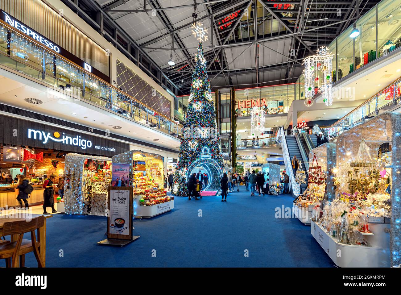 La gente cammina lungo i negozi e le bancarelle a Donau Centrum - moderno centro commerciale decorato per le vacanze di Natale a Vienna, Austria. Foto Stock