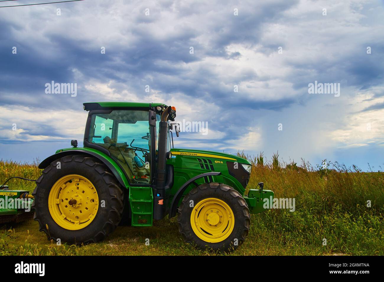 Attrezzatura trattore agricola John Deer con nuvole tempestose Foto Stock