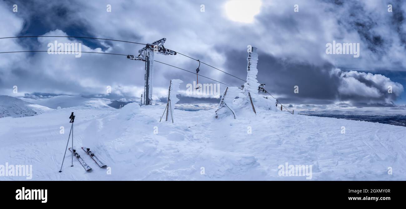 Panorama panoramico di ghiacciato sotto forte vento di neve e skilift in cima alla montagna, uno par di sci da vicino foto di impianti di risalita stazione Foto Stock