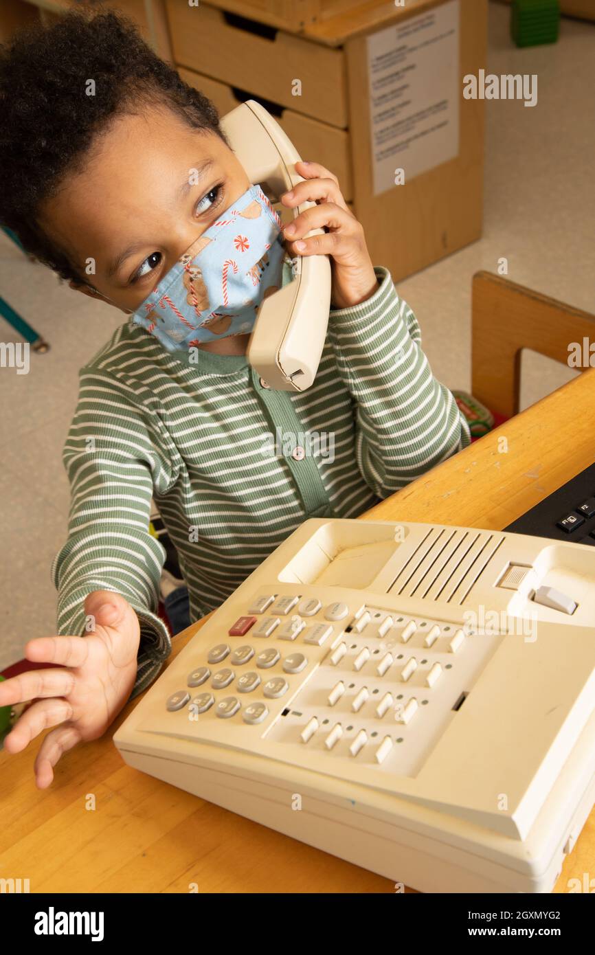 Istruzione Preschool 3-4 anni ragazzo parlare al telefono in famiglia area indossare maschera per proteggere contro Covid-19 Foto Stock