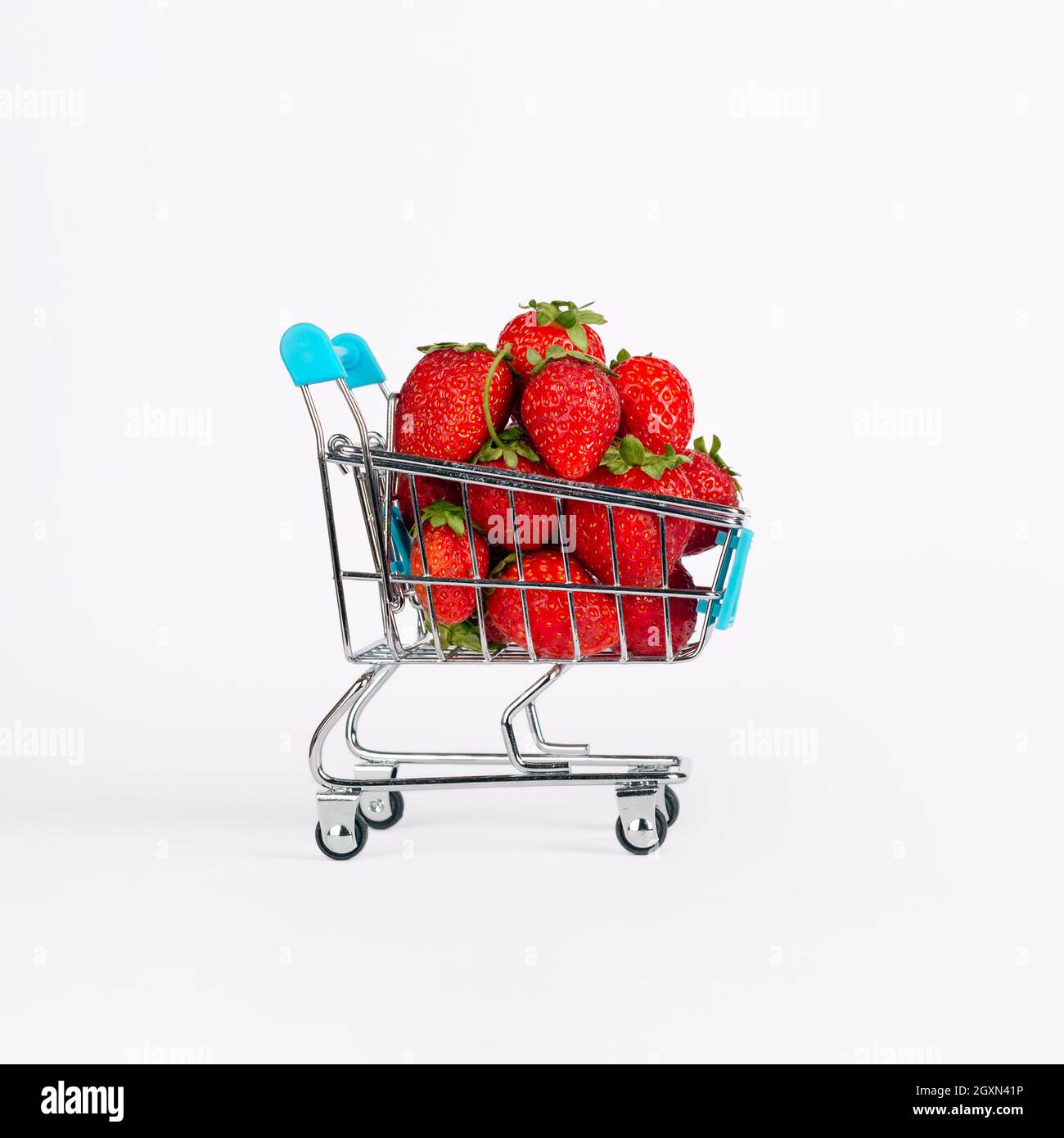 Carrello giocattolo o carrello pieno di grandi fragole rosse mature isolate su sfondo bianco. Concetto di vendita del raccolto di Berry Foto Stock