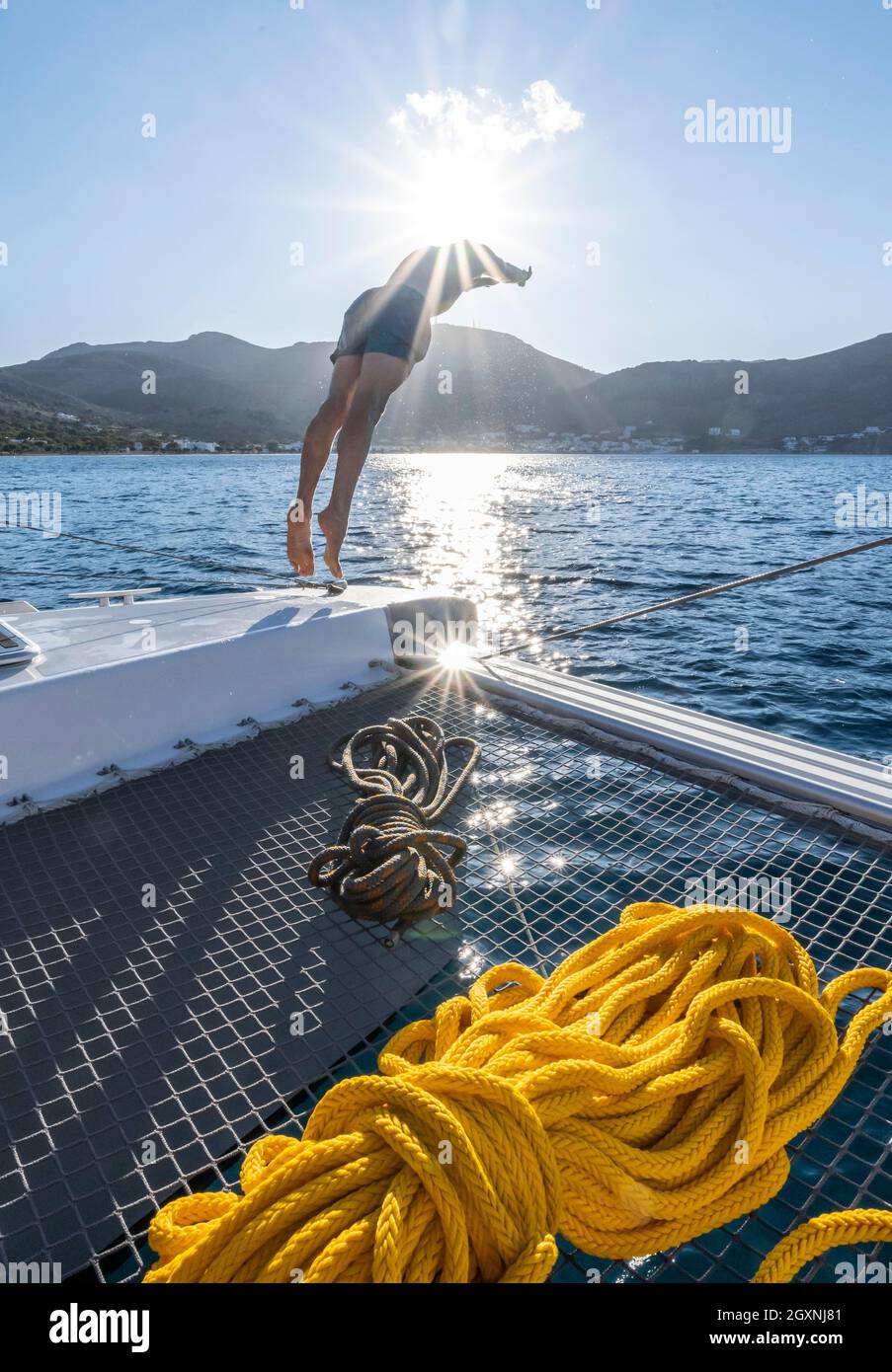 Il giovane uomo salta in acqua, corde su un catamarano a vela, Sun Star, gita in barca a vela, Tilos, Dodecaneso, Grecia Foto Stock